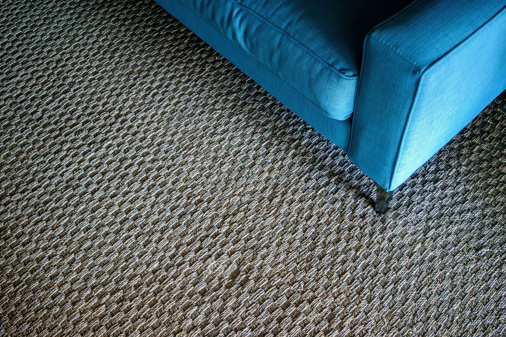 A modern blue sofa corner on a textured woven carpet, capturing a minimalist design.