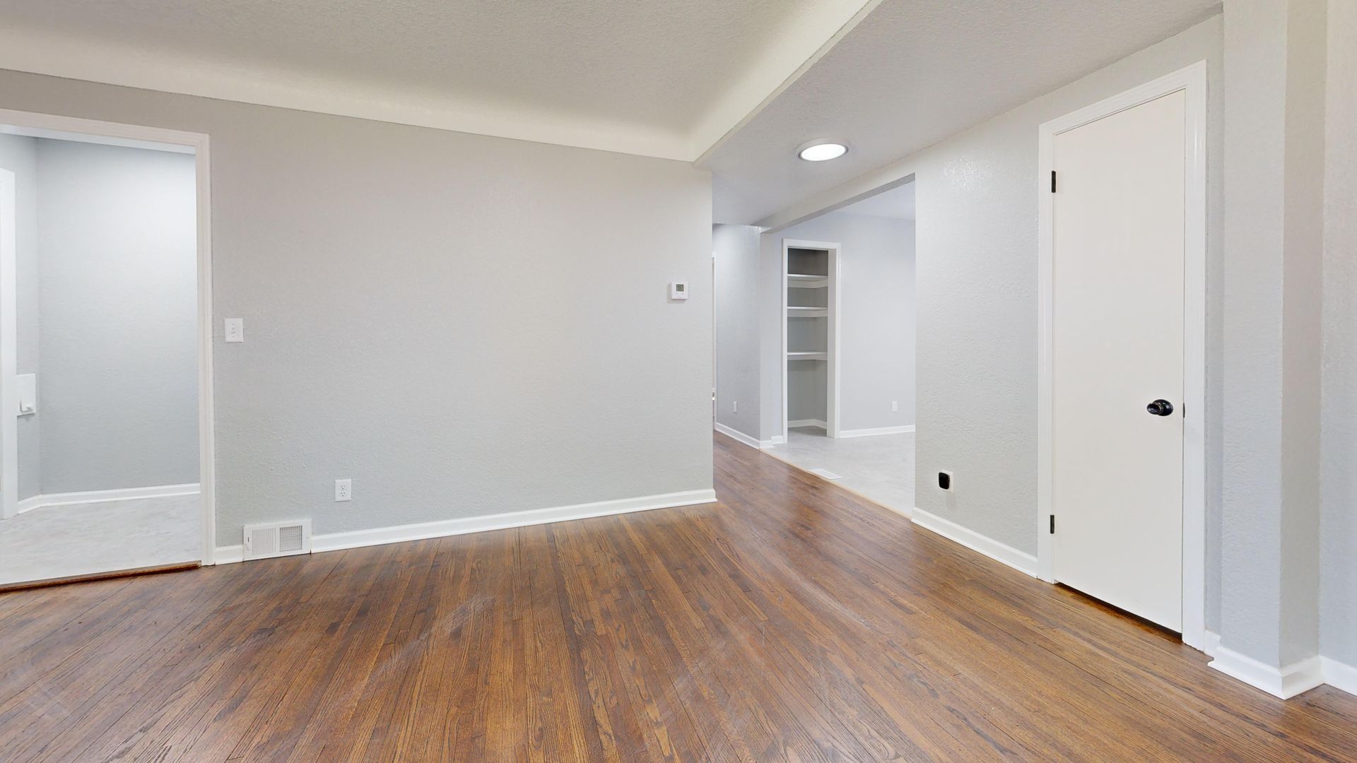 Bright empty room with wooden floor, perfect for real estate listings.